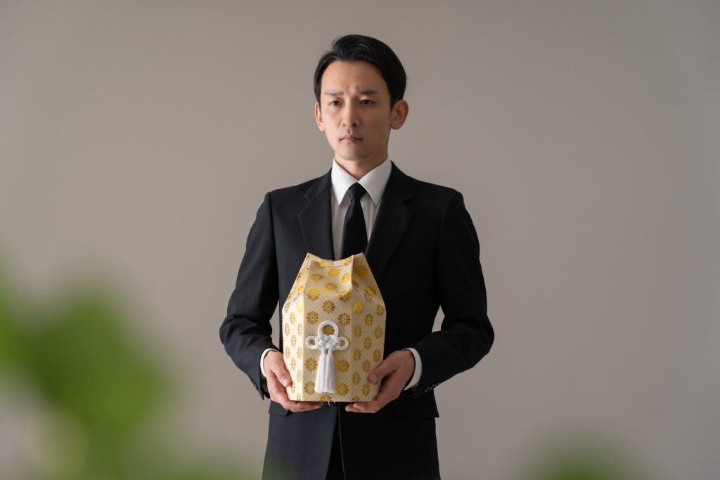 骨壺を持つ男性