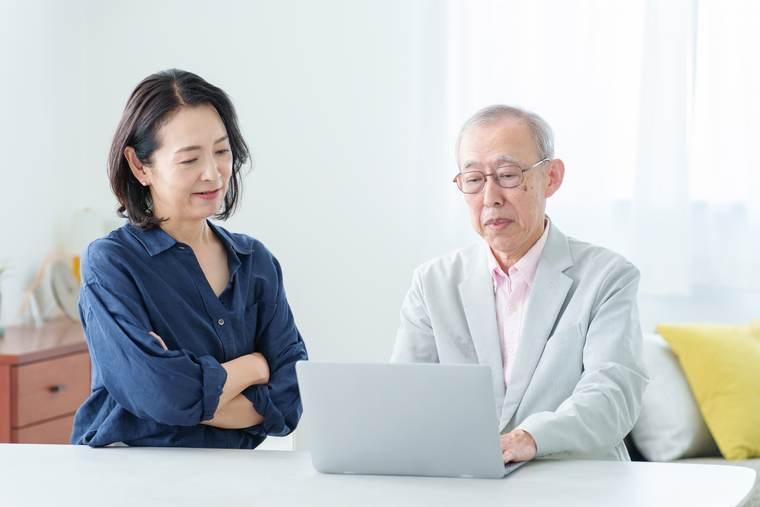 ノートパソコンで相談する高齢の夫婦
