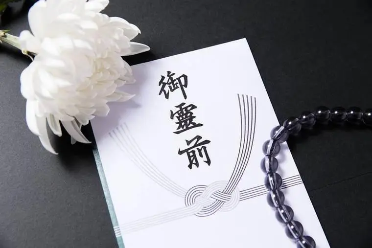 白菊と数珠を添えた御霊前の不祝儀袋