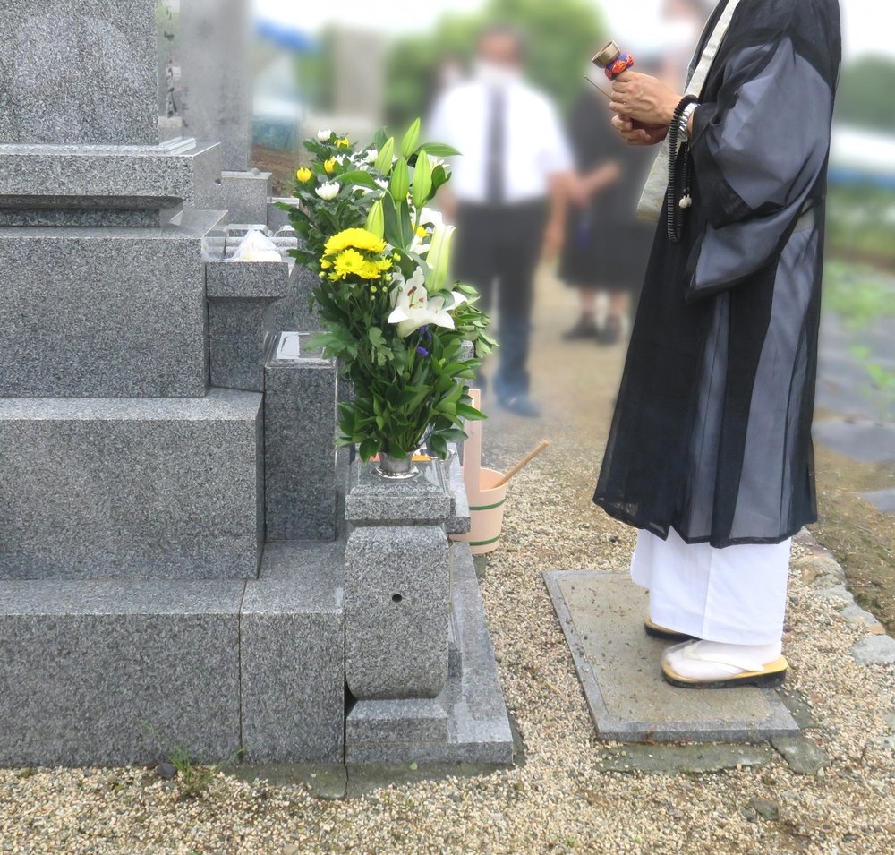 お墓の前で読経する僧侶
